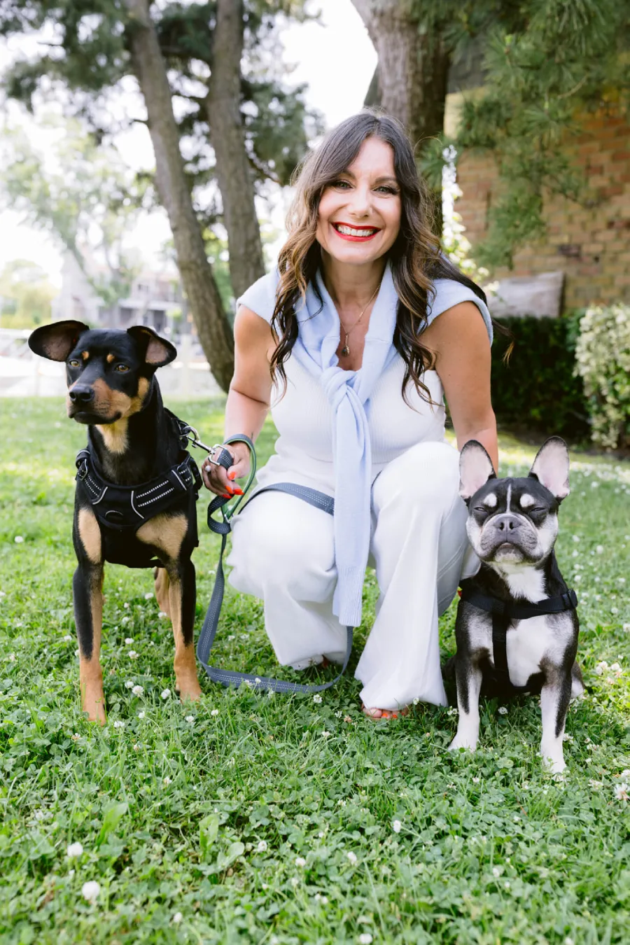 A woman holding a leash with two dogs.