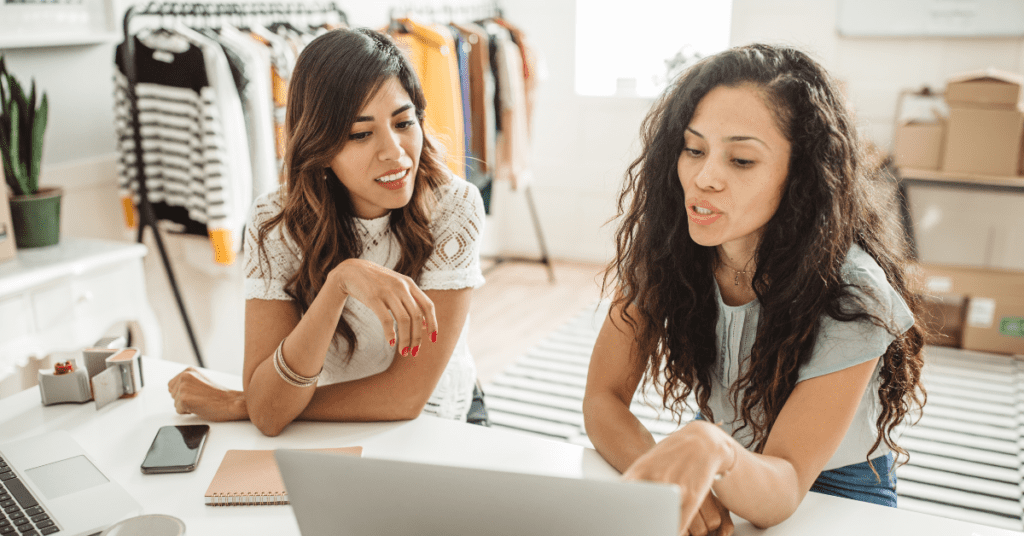 Two women looking at a laptop screen having a discussion. 